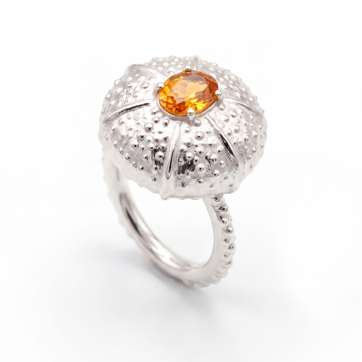 A white gold ring featuring a textured, sea urchin-inspired dome setting with a central oval orange sapphire, shown on a clean white background.