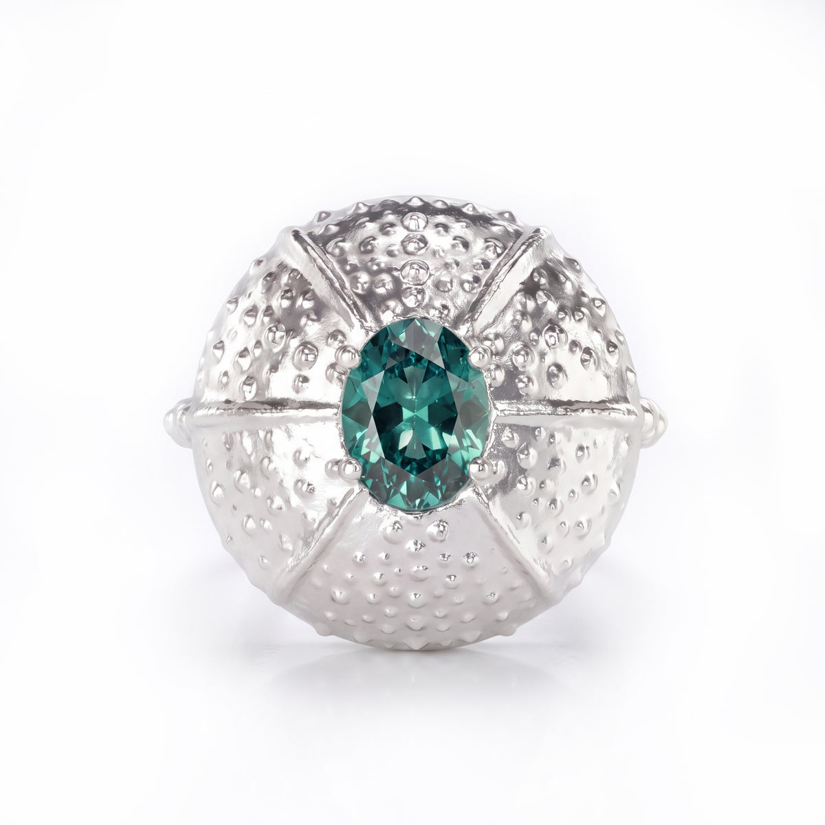 A white gold ring featuring a textured, sea urchin-inspired dome setting with a central teal sapphire, shown on a clean white background.