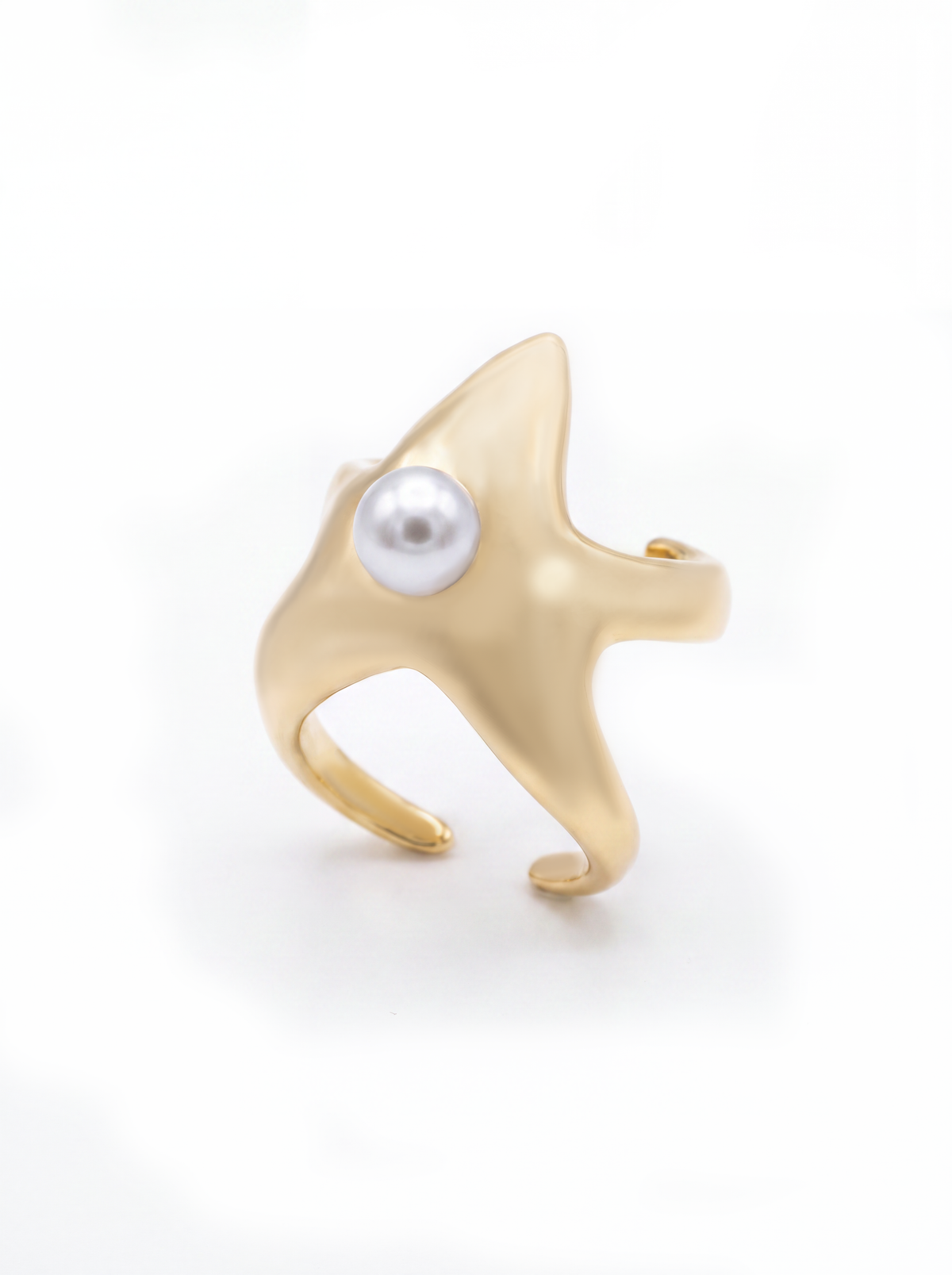 A gold starfish-shaped cuff featuring a single white pearl set in the center, photographed on a clean white background.